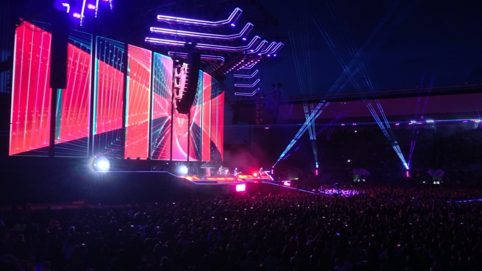 Un grand concert de nuit, écrans géants et faisceaux lumineux au-dessus de la foule