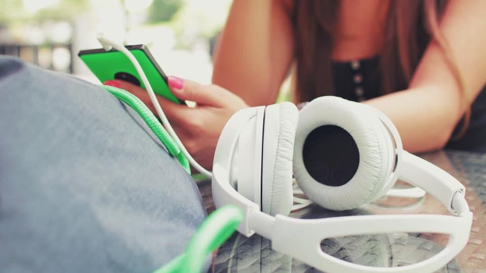 Une personne écoute de la musique avec un casque et un smartphone